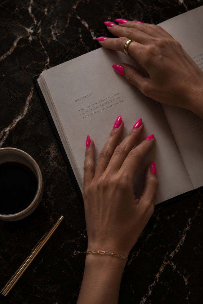 Woman writing in a journal on a dark marble surface, representing identity work and reinvention